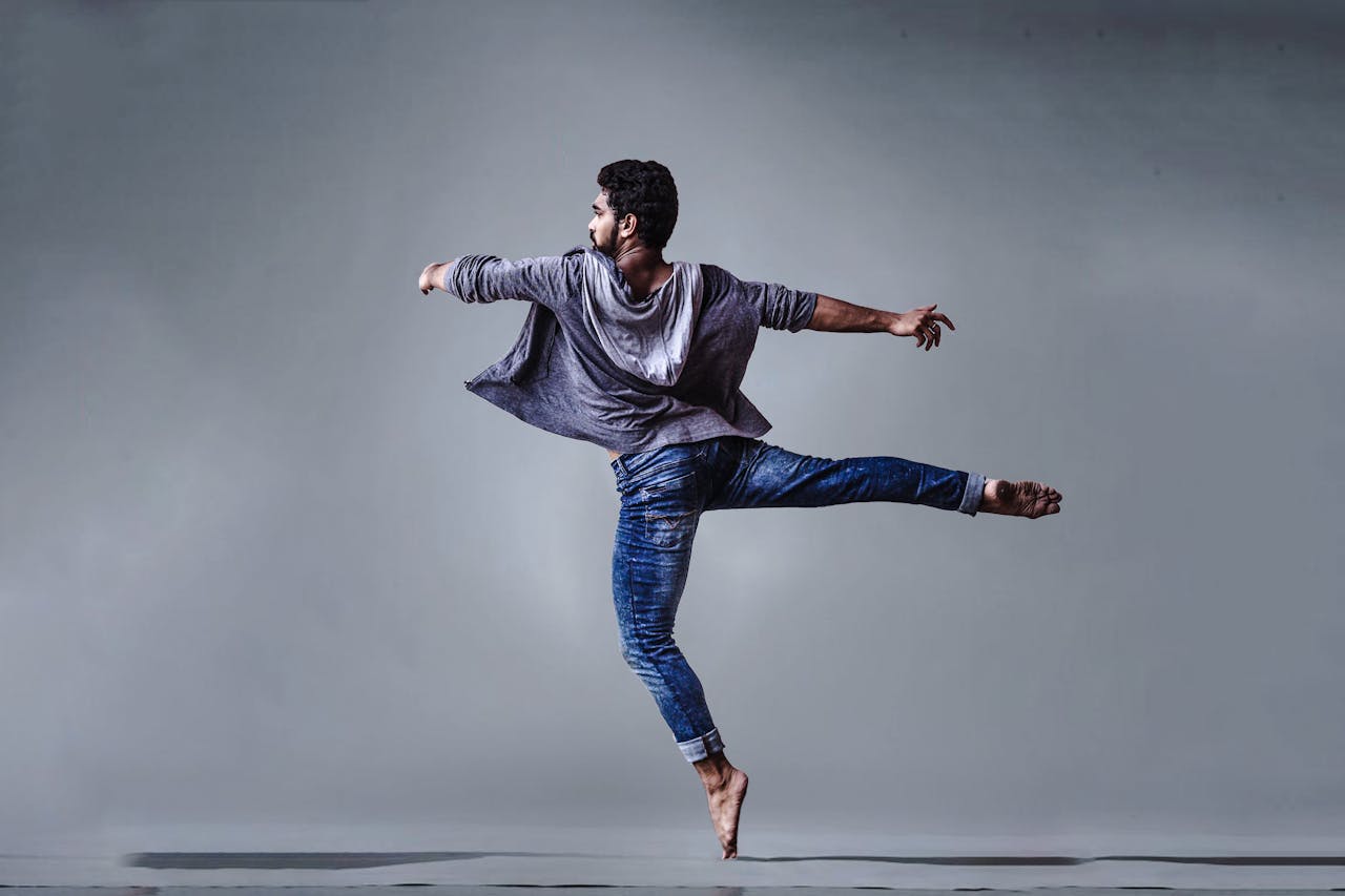 why-choose-us A male dancer executing a high jump in a studio setting, showcasing grace and agility.
