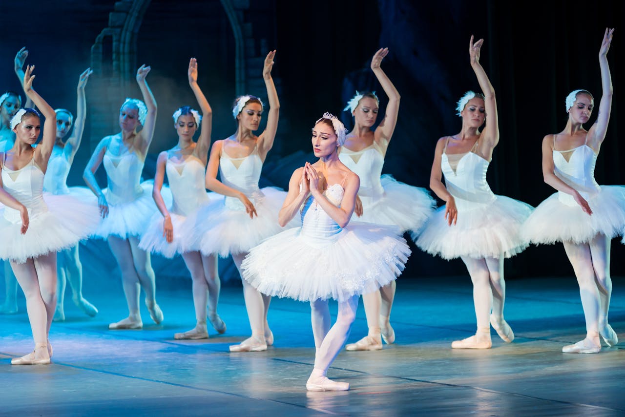 home-hero Elegant ballerinas performing Swan Lake ballet on stage in classic tutus.